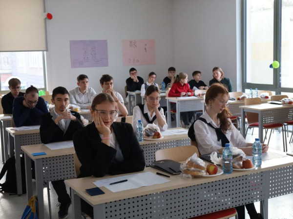 Uczniowie siedzą za stolikami