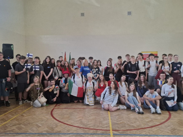 Grupowe zdjęcie uszestników Gry. Duża grupa uczniów i opiekunów pozuje do zdjęcia na sali gimnastycznej.