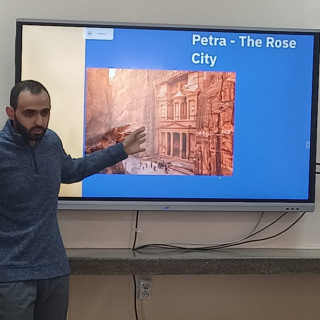 Gość z Jordanii przy tablicy z prezentacją Jordanii.