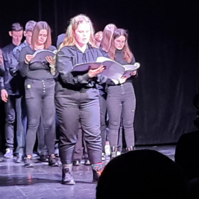 Na scenie teatru młodzież czyta Antygonę.