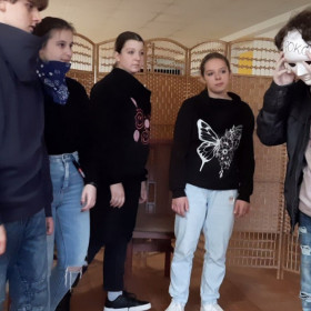 Młodzież stoi wokół chłopca w masce