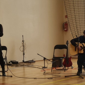 Uczennica śpiewa, nauczyciel akompaniuje na gitarze.