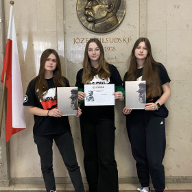 Trzy finalistki konkursu na tle tablicy Józefa Piłsudskiego