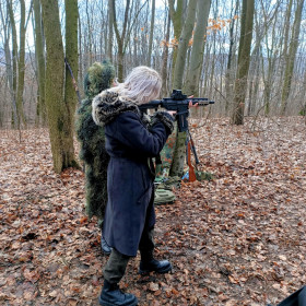 W lesie uczennica składająca się do strzału w ramach ćwiczeń z bronią