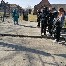 Druga grupa słucha przewodnika na placu przed wejściem na teren obozu koncentracyjnego.