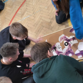 Młodzież na podłodze układa puzzle.