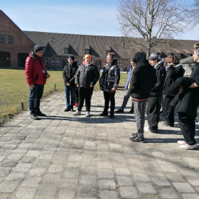 Pierwsza grupa słucha przewodnika na placu przed wejściem na teren obozu koncentracyjnego.