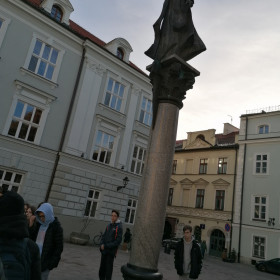 Uczniowie stoją obok pomnika Piotra Skargi.