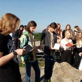 Uczeń czyta fragment książki Nad Niemnem w tle grupa uczniów słucha