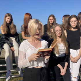 Uczennica czyta fragment Nad Niemnem w tle grupa uczennic słucha