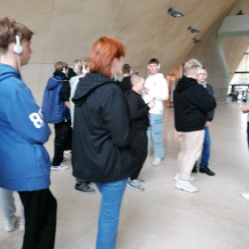 Uczniowie w słuchawkach   słuchają w muzeum przewodniczki
