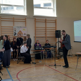 Ksiądz grający na gitarze i schola animująca śpiew
