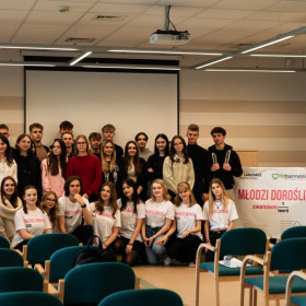 Grupa uczniów i nauczycieli w koszulkach z napisami: Młodzi dorośli.