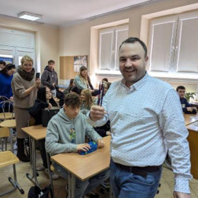 Uśmiechnięty pan Robert na tle uczniów