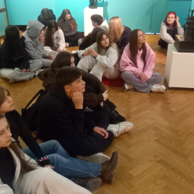 Uczniowie siedzą na podłodze w muzeum