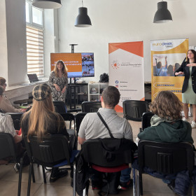 Uczestnicy wydarzenia stoją w tle widać banery Centrum Wolontariatu