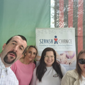 Uczestnicy pikniku stoją na tle baneru fundacji 