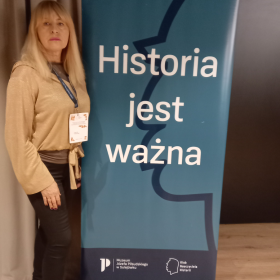 Nauczycielka przy banerze z napisem Historia jest ważna