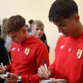 piłkarze rozdają autografy uczniom