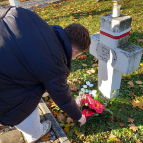 Uczeń kładzie wiązankę na grobie