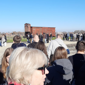 uczniowie stoją na placu w Brzezince oglądając drewniany wagon