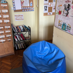 kacik czytelniczy, na pierwszym planie widoczna jest duża niebieska pufa w tle półka z książkami