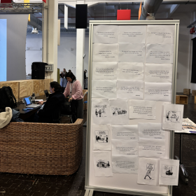 na zdjęciu widać nowoczesną przestrzeń o charakterze warsztatowym obok umieszczona jest duża tablica z przypiętymi cytatami i zadaniami do wykonania