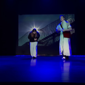 Pasterz przeprowadza Emanuelę przez więzienie na scenie