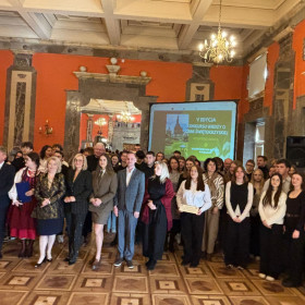 wszyscy uczestnicy wydarzenia stoją na tle banneru o konkursie