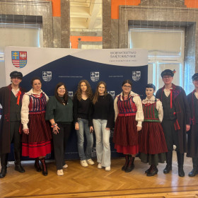 zdjęcie uczestników konkursu wraz z prowadzącymi ubranymi w stroje ludowe