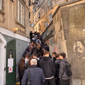 Na zdjęciu widoczna jest wąska ulica miasta po której spacerują uczniowie