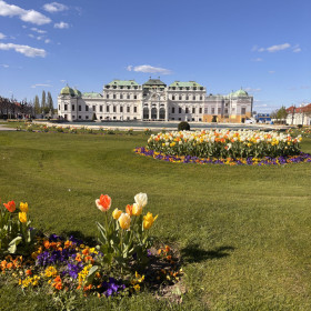 Na zdjęciu widoczny jest duży ogród z kolorowymi kwiatami przed pałacem