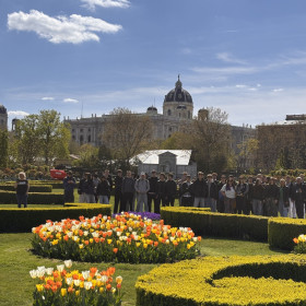 Na zdjęciu widoczny jest pałac oraz ogród w tle stoją uczestnicy wycieczki