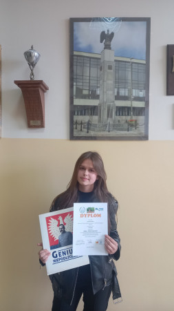 Uczennica trzyma książkę i dyplom.